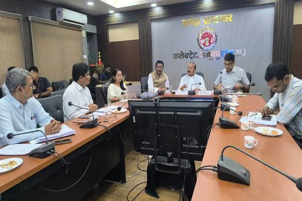 सम्मेलन कक्ष में मेज के चारों ओर बैठे अधिकारी निर्माण कार्यों की समीक्षा बैठक करते हुए